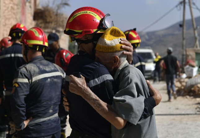 A man hugs a member of a civil protection team as it prepares to recover bodies in Imi N'Tala on September 13.