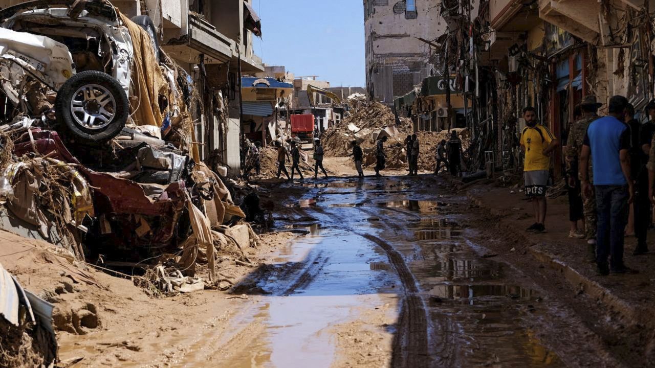People walk past houses destroyed by heavy rain and flooding in Derna, Libya, on September 13, 2023.