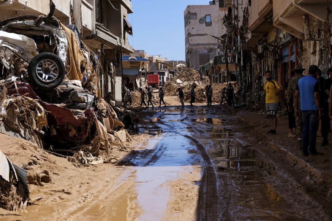 People walk past houses destroyed by heavy rain and flooding in Derna, Libya, on September 13, 2023. 