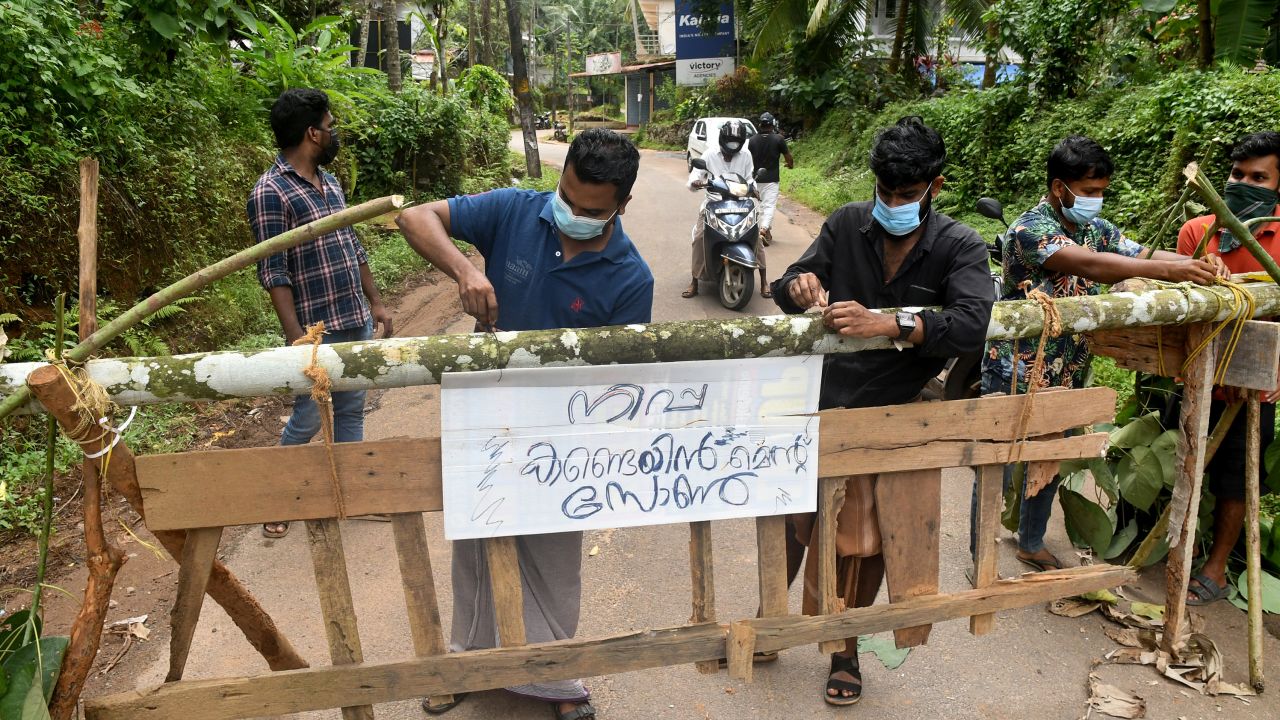 Жители поправят табела с надпис "Задържаща зона на Нипа" в квартал Кожикод, Керала, Индия, на 13 септември.