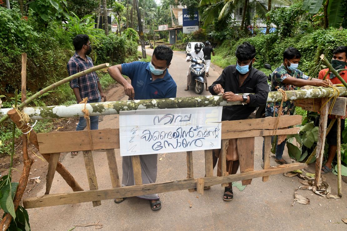 Residents fix a sign reading, "Nipah containment zone,"   in the Kozhikode district of Kerala, India, on September 13.