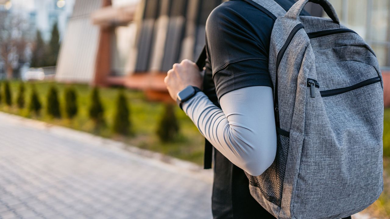 Handsome young man with a backpack walking home after a workout. Close-up.