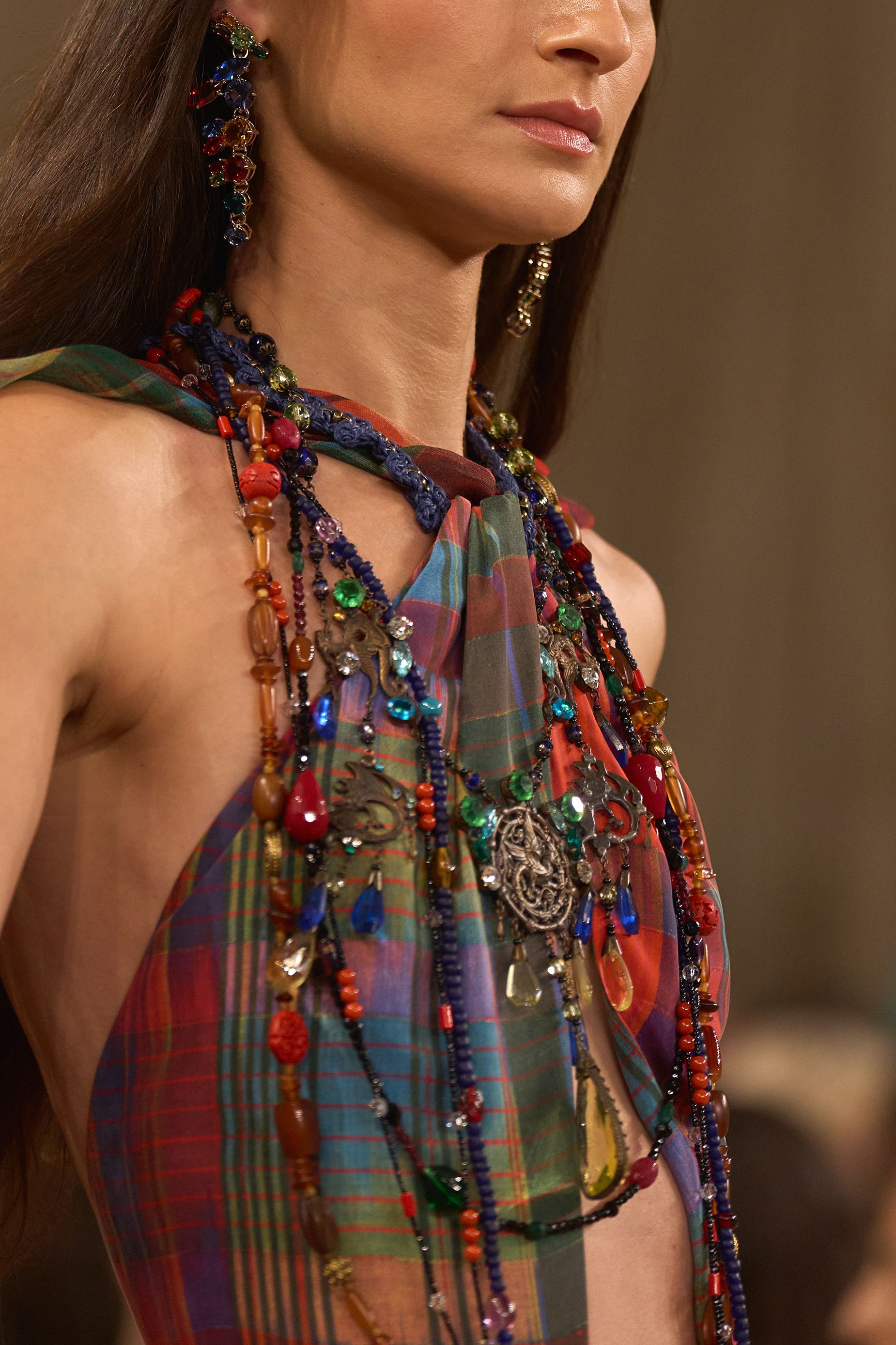 Strands of chunky beading and gems are layered atop a multicolored check bandeau top.