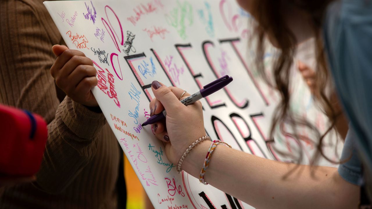 People sign a poster that reads "Elect More Women" during the Democratic rally in Glen Allen, Virginia, on September 9, 2023.