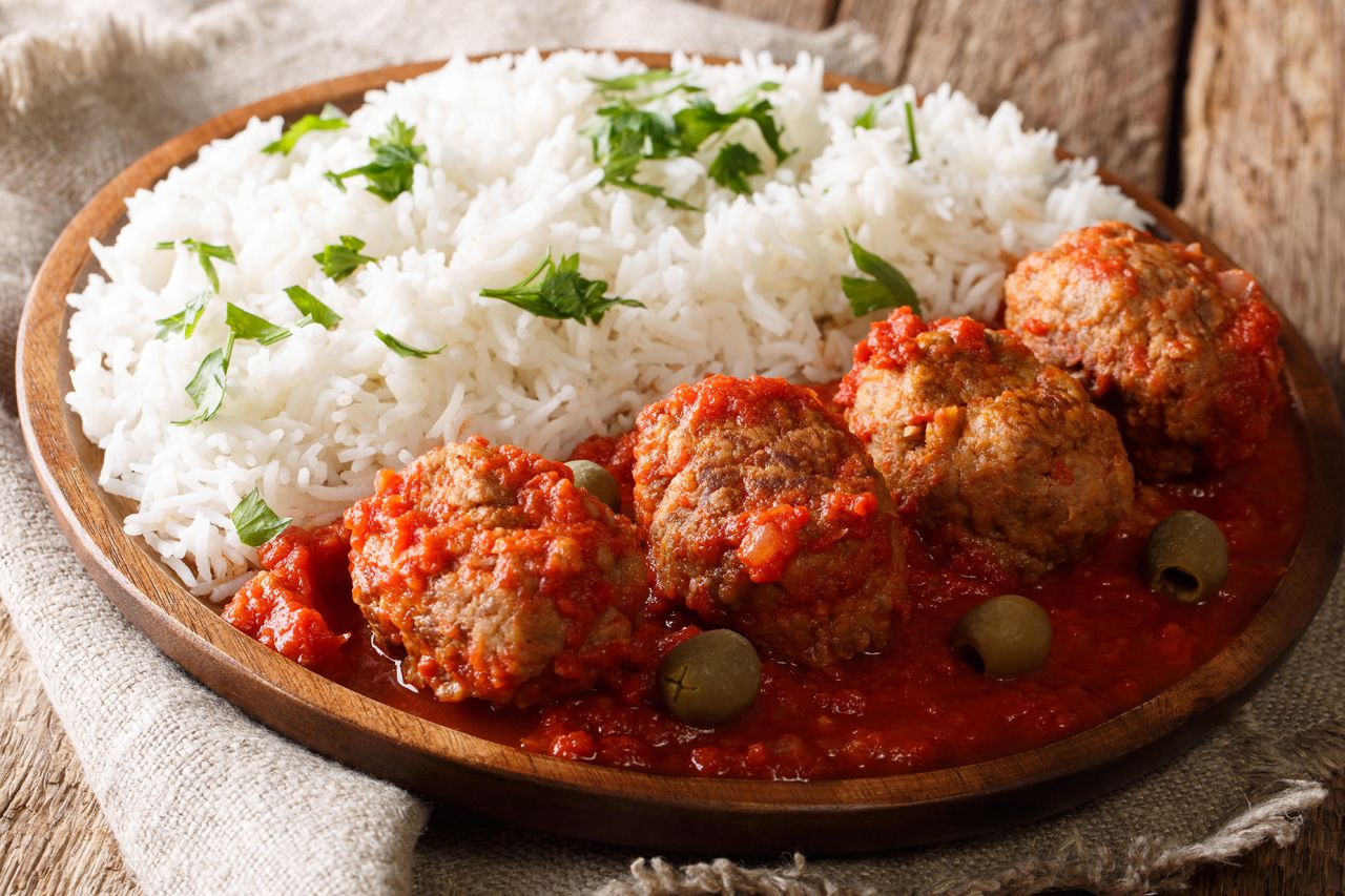 PJB0YJ Greek food: Soutzoukakia baked meat balls in spicy tomato sauce served with rice close-up on a plate on the table. horizontal