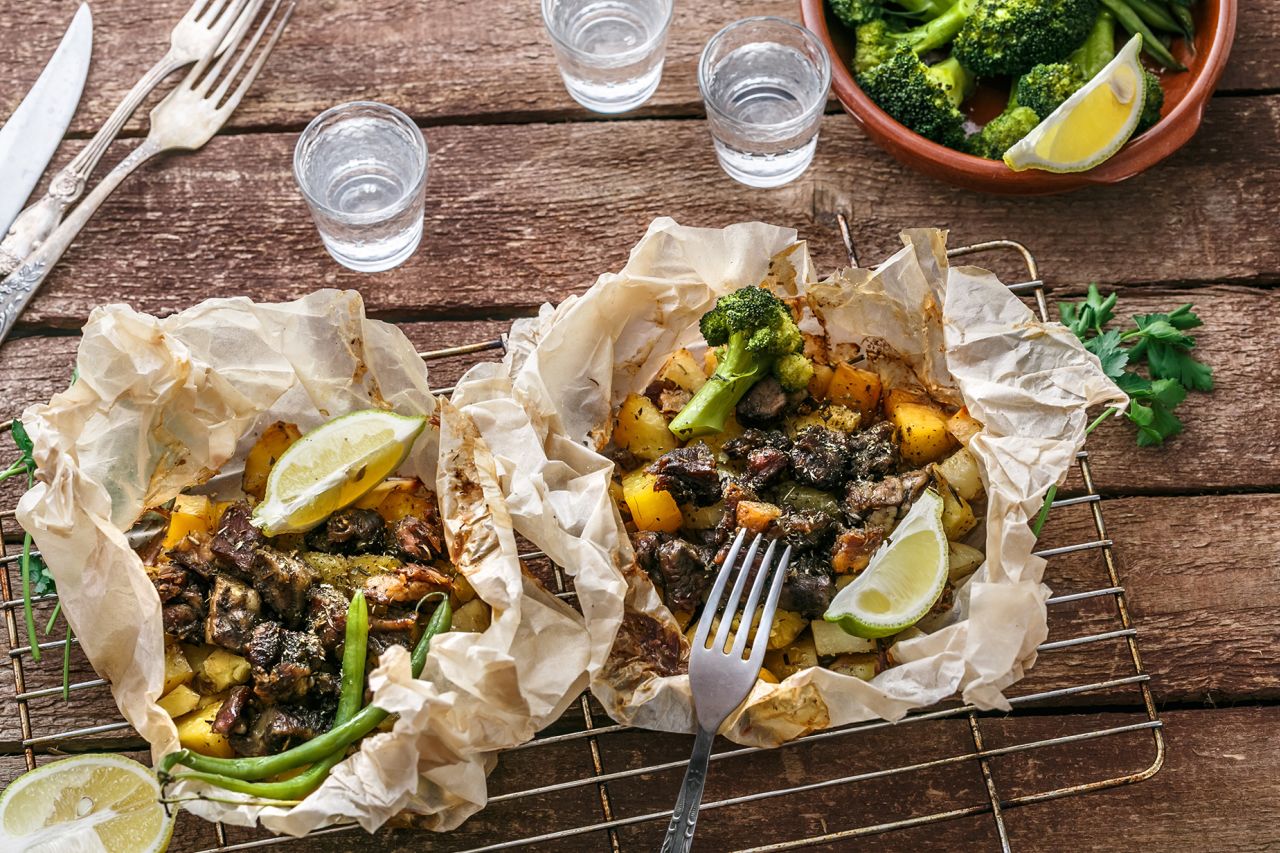 Traditional Greek kleftiko, an oven-baked lamb stew with potato, olive oil, onion, carrot, garlic and herbs, served with lemon and ouzo