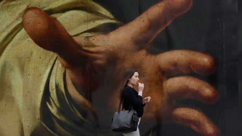 A woman walks past a poster featuring the painting of Caravaggio's "The Supper at Emmaus" outside the National Gallery, in London, Wednesday, Sept. 13, 2023. (AP Photo/Kin Cheung)