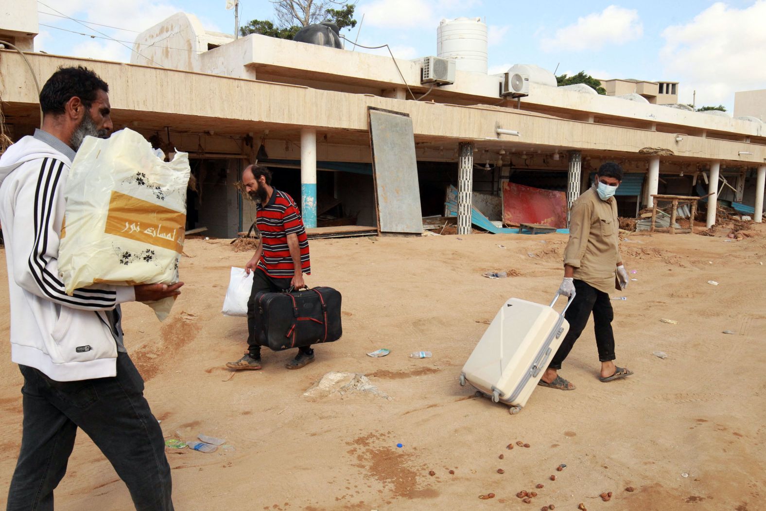 People carry some of their belongings as they walk along a muddy street on September 14.