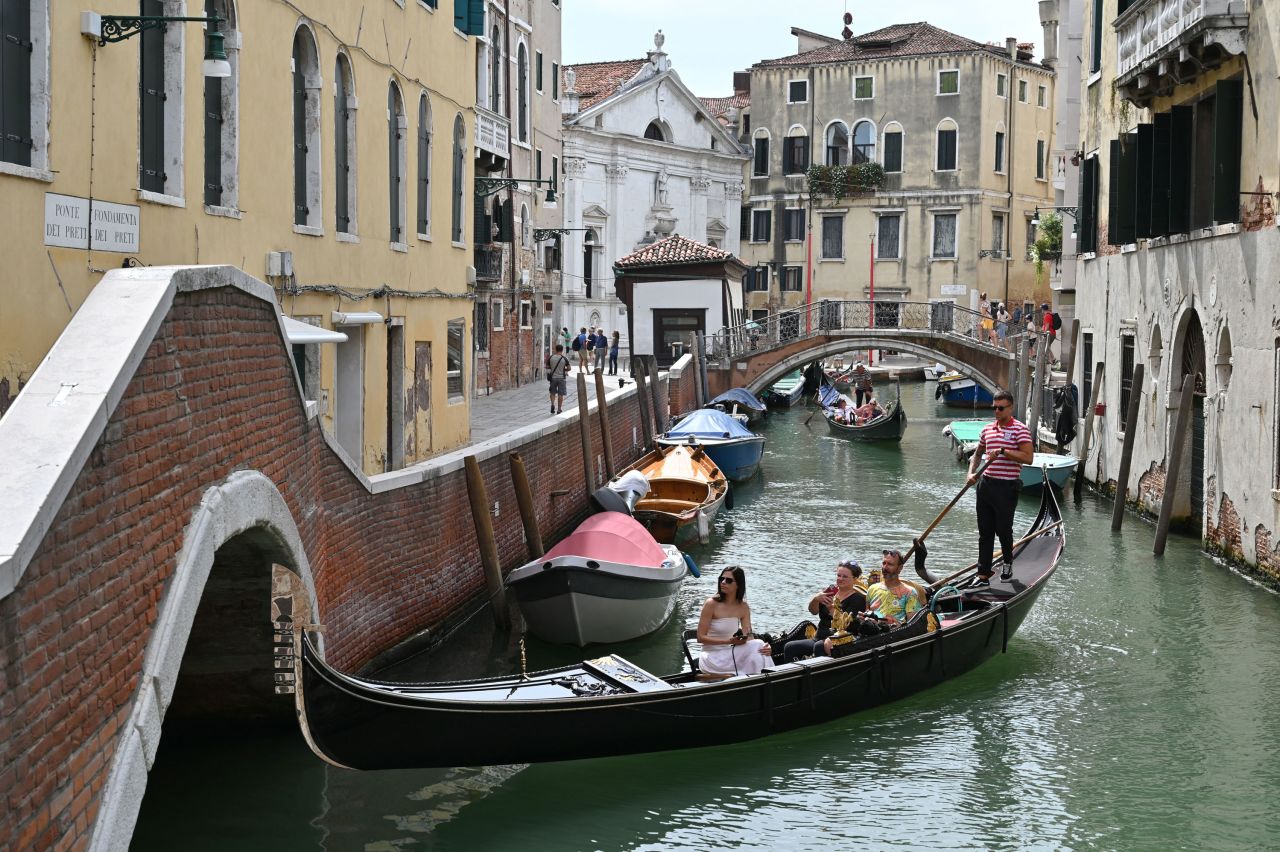 Tourists take a gondola ride across a canal in Venice on July 31.