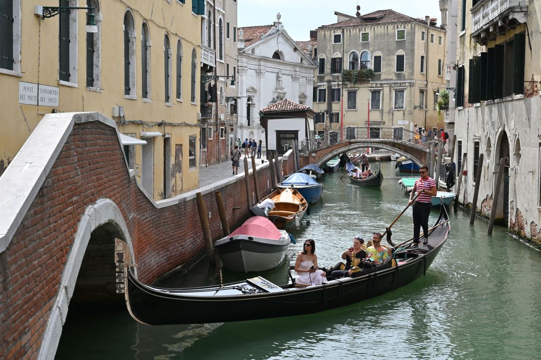 Tourists take a gondola ride across a canal in Venice on July 31.