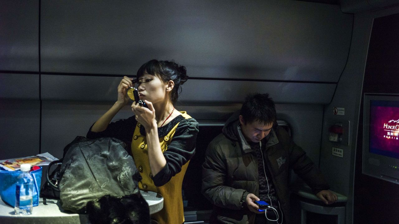 A woman puts on make-up at a railway station in Beijing on December, 12, 2014. 