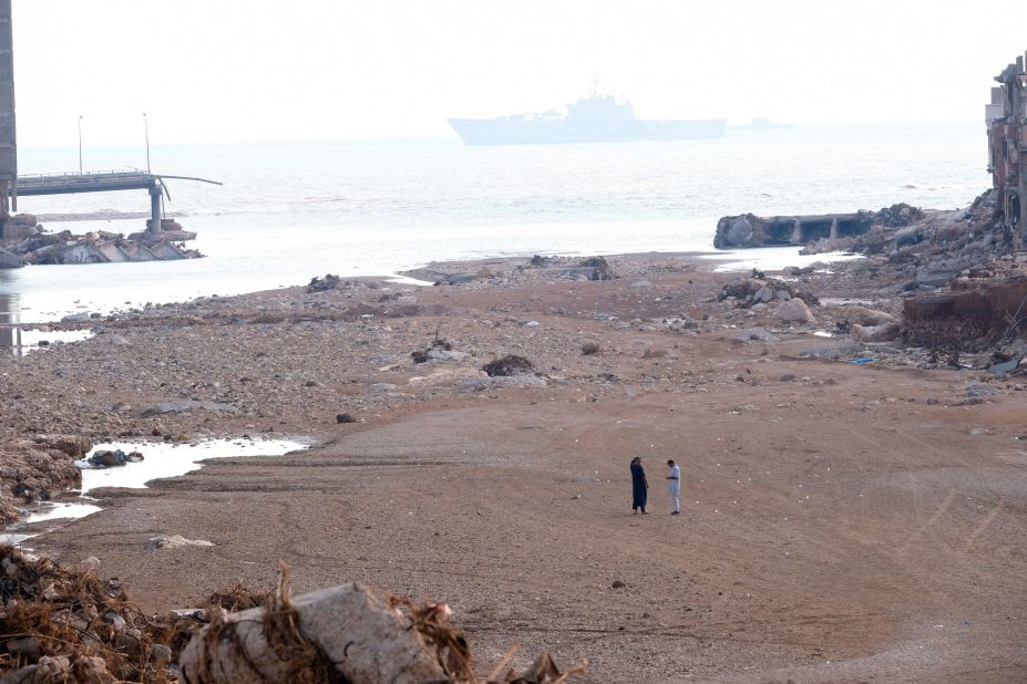 People walk across a beach surrounded by flood damage on September 16.