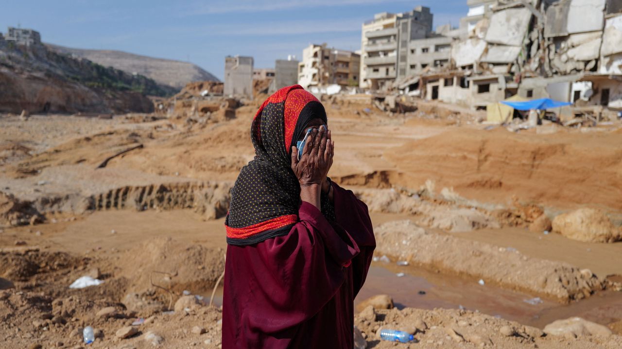 Aisha, 51, who said she lost five family members when the deadly storm hit her city, reacts as she walks past destroyed houses, in Derna, Libya on Sunday.