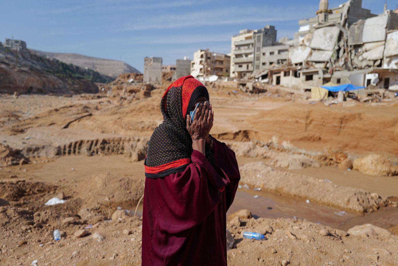 A woman who lost family members reacts as she walks past destroyed houses in Derna on September 17.