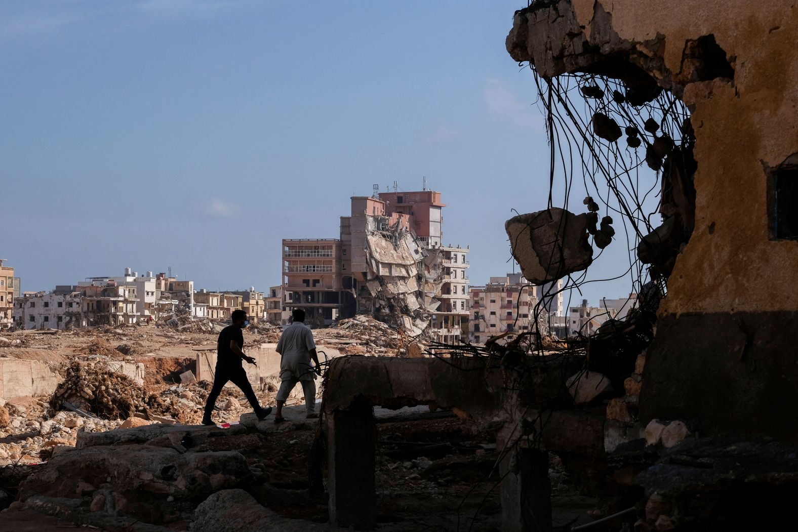 People walk through rubble and debris in Derna on September 17.