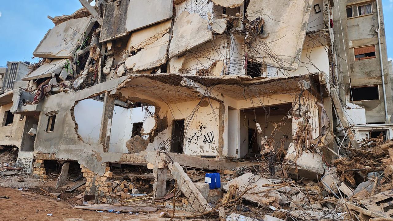 डर्ना, लीबिया में बाढ़ से क्षतिग्रस्त एक इमारत पर भित्तिचित्र लिखा है 