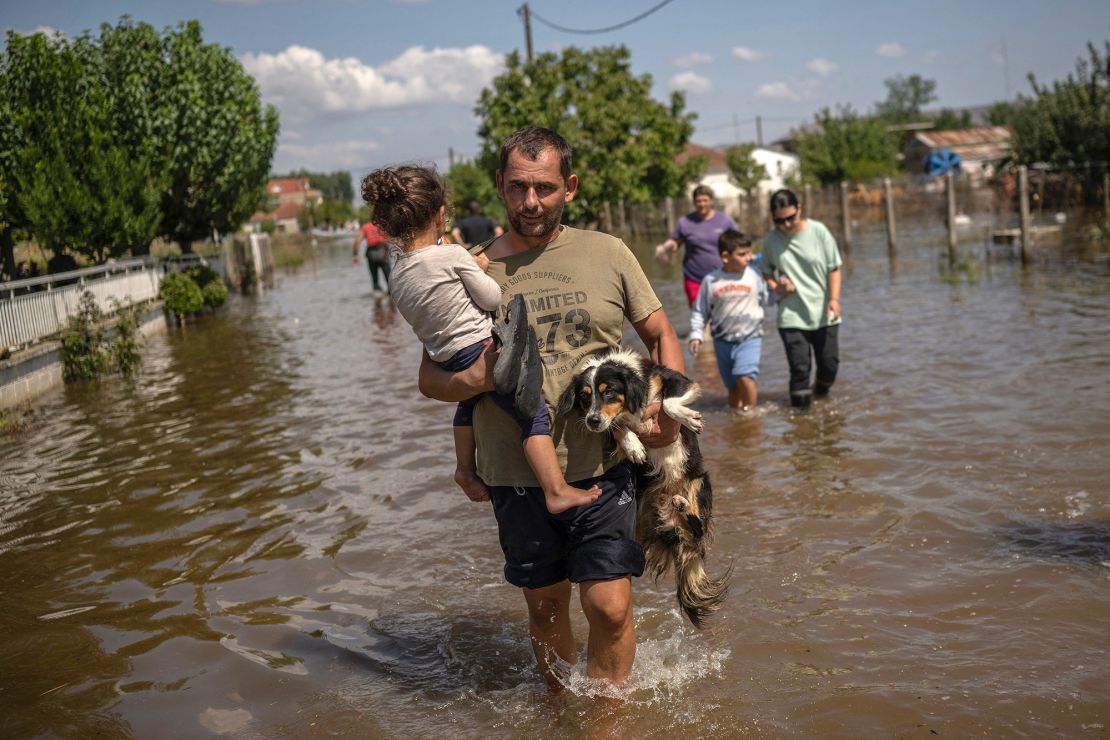 A man carries a girl and a dog in the flooded village of Palamas near the city of Karditsa, central Greece, on September 8, 2023.