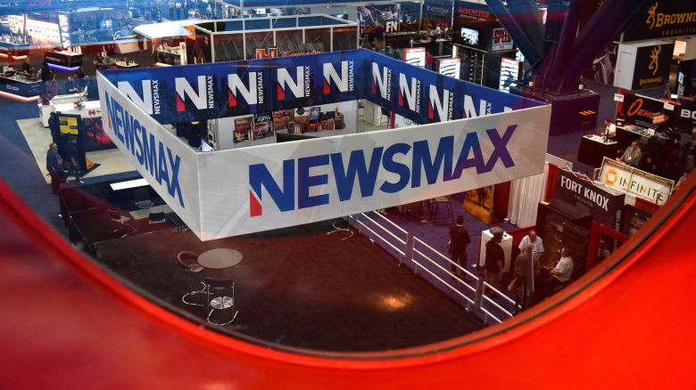 FILE PHOTO: A Newsmax booth broadcasts as attendees try out the guns on display at the National Rifle Association (NRA) annual convention in Houston, Texas, U.S. May 29, 2022. Picture taken through glass. REUTERS/Callaghan O'Hare/File Photo