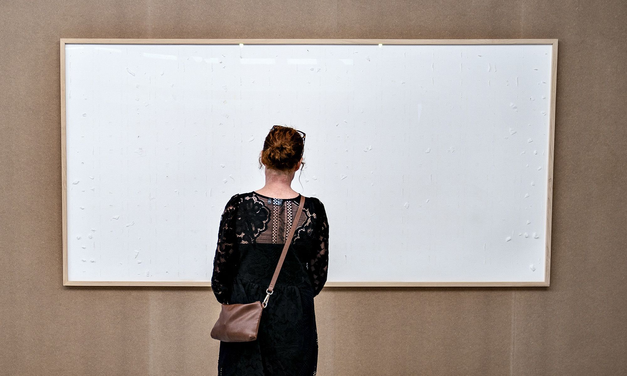 A woman stands in front of an empty frame hung up at the Kunsten Museum in Aalborg, Denmark, on September 28 2021. - The Danish museum loaned an artist $84,000 in cash to recreate old artworks of his using the banknotes, but the boxes he sent only contained blank canvasses and a new title: "Take the Money and Run". Danish artist Jens Haaning had done just that, pocketing the money the Kunsten Museum in the western city of Aalborg had loaned him to reproduce two works that used Danish kroner and euros to represent the annual salary in Denmark and Austria. - Denmark OUT / RESTRICTED TO EDITORIAL USE - MANDATORY MENTION OF THE ARTIST UPON PUBLICATION - TO ILLUSTRATE THE EVENT AS SPECIFIED IN THE CAPTION (Photo by Henning Bagger / Ritzau Scanpix / AFP) / Denmark OUT / RESTRICTED TO EDITORIAL USE - MANDATORY MENTION OF THE ARTIST UPON PUBLICATION - TO ILLUSTRATE THE EVENT AS SPECIFIED IN THE CAPTION / Denmark OUT / RESTRICTED TO EDITORIAL USE - MANDATORY MENTION OF THE ARTIST UPON PUBLICATION - TO ILLUSTRATE THE EVENT AS SPECIFIED IN THE CAPTION (Photo by HENNING BAGGER/Ritzau Scanpix/AFP via Getty Images)