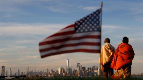 The sun sets on the skyline of lower Manhattan, the Statue of Liberty and the Empire State Building in New York City as an American flag flies at the Tear Drop 9/11 Memorial on June 9, 2019 in Bayonne, New Jersey.