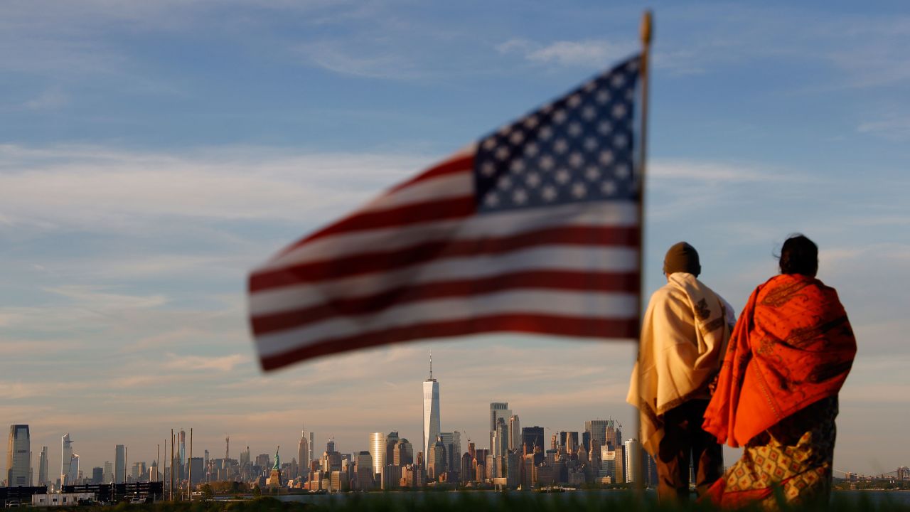 The sun sets on the skyline of lower Manhattan in New York City as an American flag flies at the Tear Drop Memorial in Bayonne, New Jersey, on June 9, 2019.