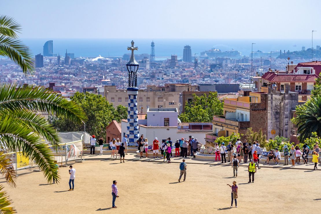 2A1DPGD BARCELONA, SPAIN-SEPTEMBER 20, 2019: Turists walking iside of Park Guell, aerial view on the panoramic view of Barcelona background