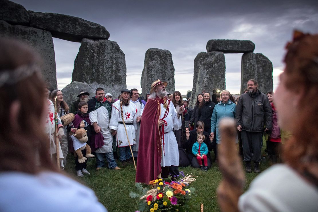 WILTSHIRE, ENGLAND - SEPTEMBER 23:  Rollo Maughfling, Archdruid of Stonehenge and Britain (C) conducts a ceremony as druids, pagans and revellers gather in the centre at Stonehenge, hoping to see the sun rise, as they take part in a autumn equinox celebrations at the ancient neolithic monument of Stonehenge near Amesbury on September 23, 2017 in Wiltshire, England. Several hundred people gathered at sunrise ar the famous historic stone circle, a UNESCO listed ancient monument, to celebrate the equinox which is a specific moment in time that occurs twice a year when the Earth tilts neither towards (summer) or away (winter) from the sun in either the northern or southern hemisphere. Although yesterday marked the actual meteorological calendar change from summer to autumn, for druids, the following dawn is when they celebrate 'the dawning of the new season' following the day of equal night, which it is named after.  (Photo by Matt Cardy/Getty Images)