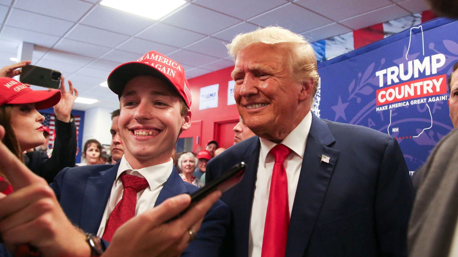 Former President and Republican presidential candidate Donald Trump speaks takes a selfie with UNH student and campaign intern David Andritsakis during the opening of his campaign headquaters in Manchester, New Hampshire, June 27, 2023.   