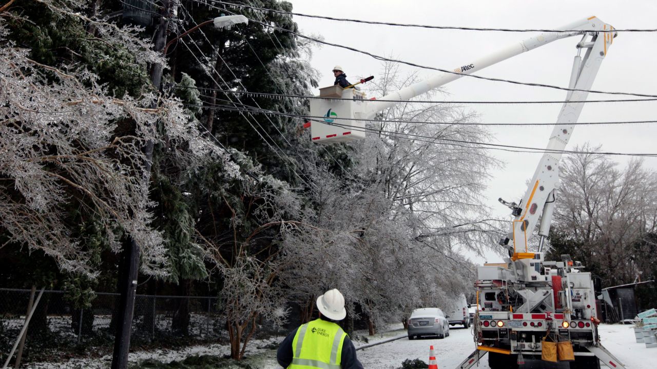 Los trabajadores de servicios públicos tienden a tender cables eléctricos abrumados por la nieve y el hielo de una tormenta invernal en Raleigh, Carolina del Norte, el 23 de enero de 2016. 