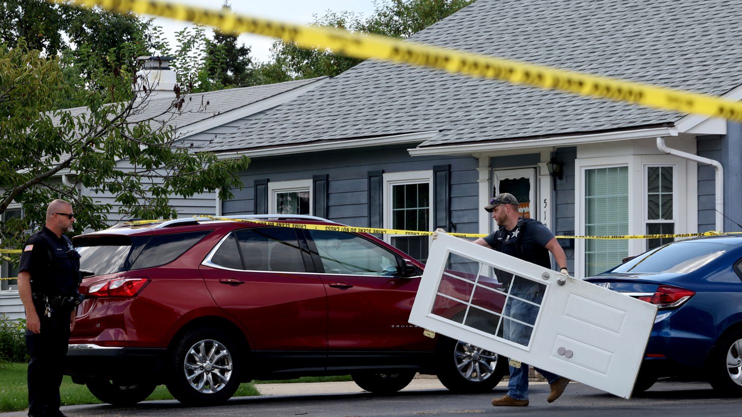 A police officer on Monday carries a door from a home where four people were found slain in Romeoville, Illinois.