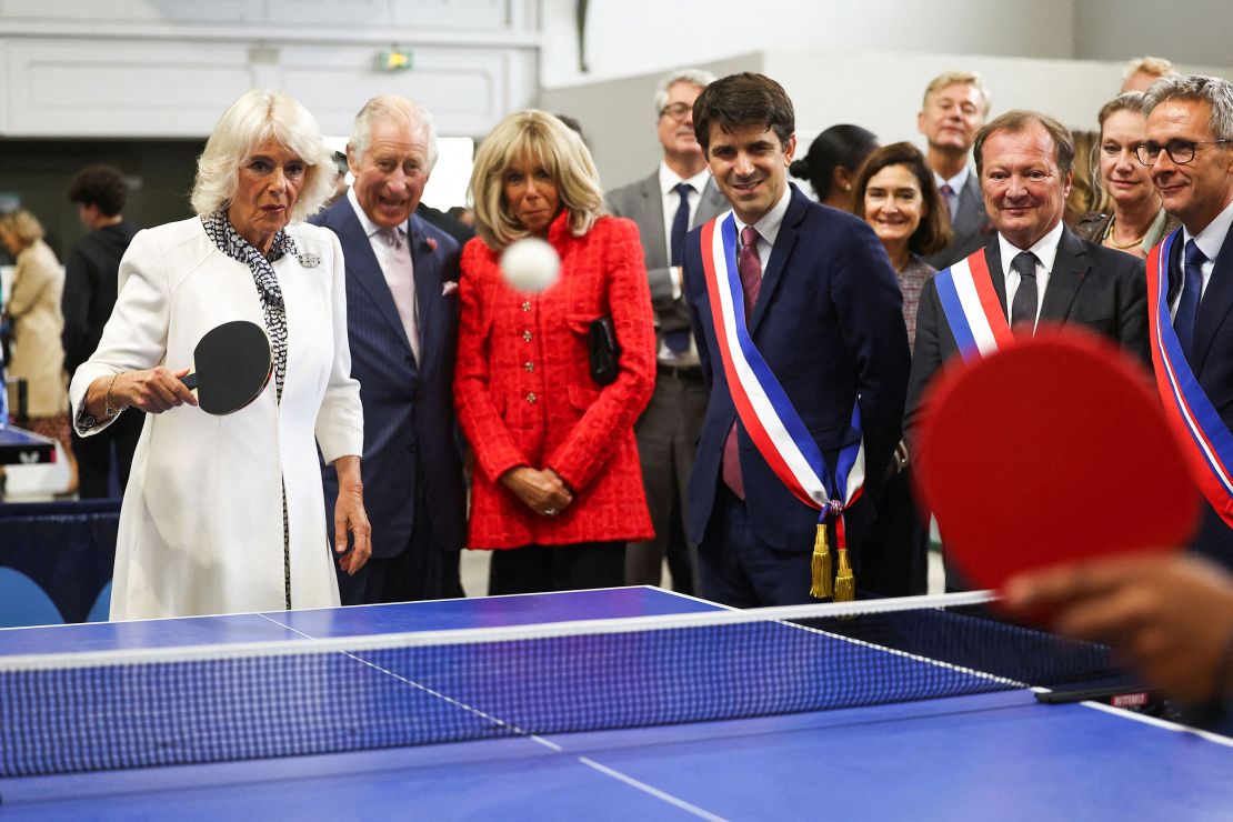 Queen Camilla plays table tennis during a visit to France's national stadium and venue for next year's Olympic Games.