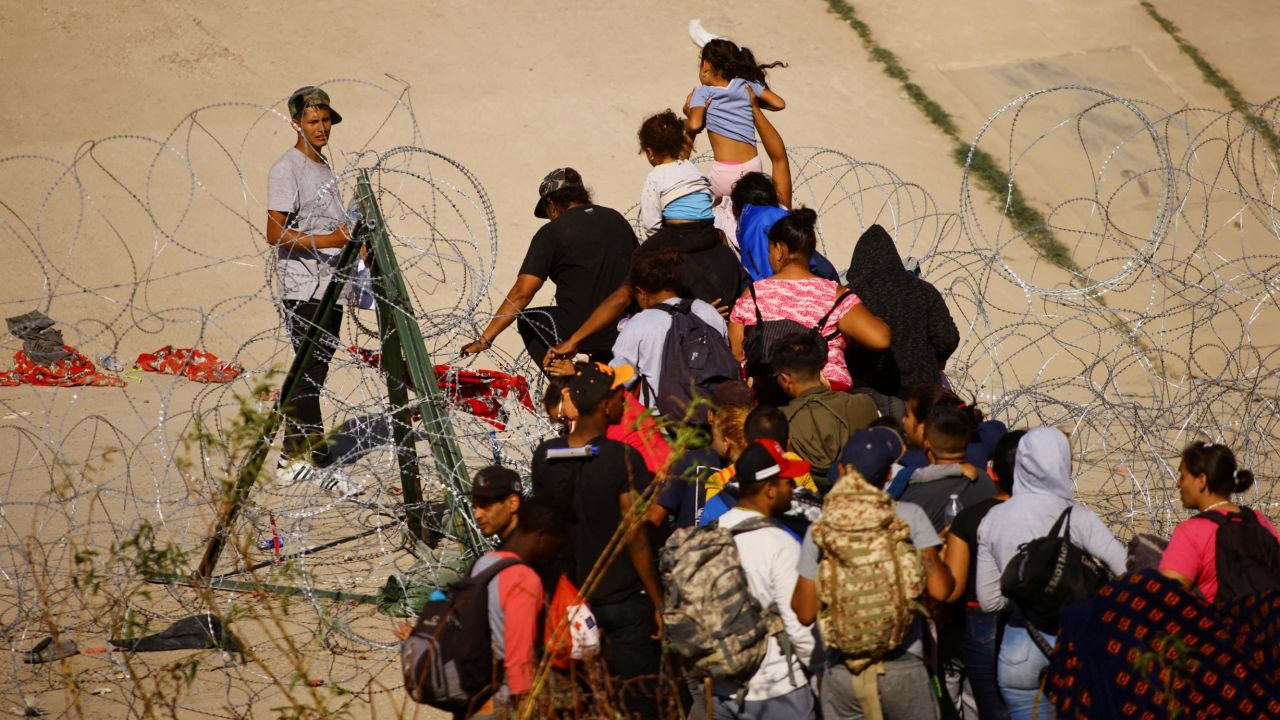 Migrants seeking asylum in the United States try to cross a razor wire fence deployed to inhibit the crossing of migrants into the United States, near a border wall on the banks of the Rio Bravo River, on the border between the U.S. and Mexico, as seen from Ciudad Juarez, Mexico September 18, 2023. REUTERS/Jose Luis Gonzalez     TPX IMAGES OF THE DAY