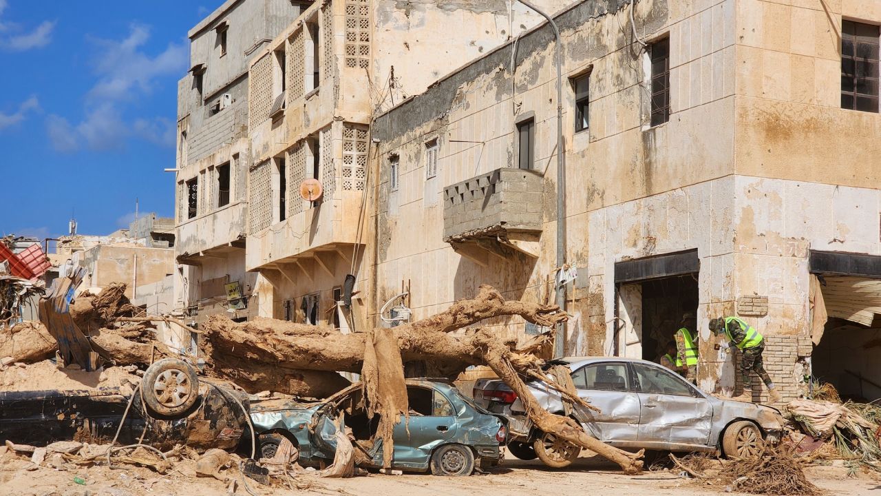 Piles of cars and trees brought by the water block streets in Derna. 