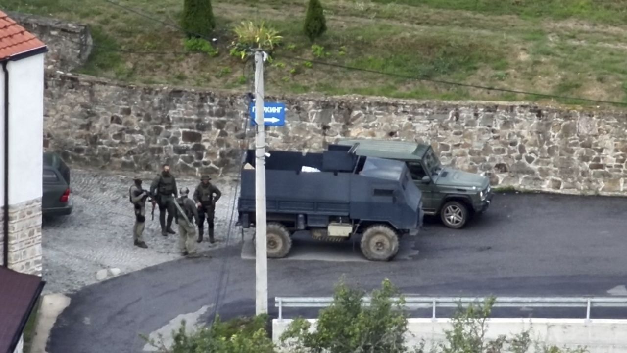 Косовска полиция и група въоръжени, маскирани мъже стоят пред манастира Банска в Северно Косово.