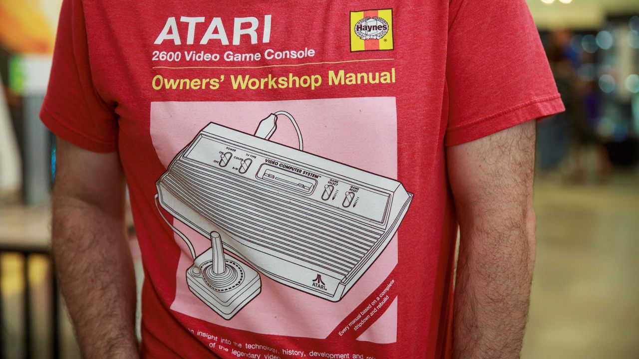  На тази снимка, направена на 12 август 2017 г., посетител позира с тениска, изобразяваща конзола за видеоигри Atari 2600 от началото на 80-те години, по време на изложението за игри Retro.HK в Хонг Конг. class=