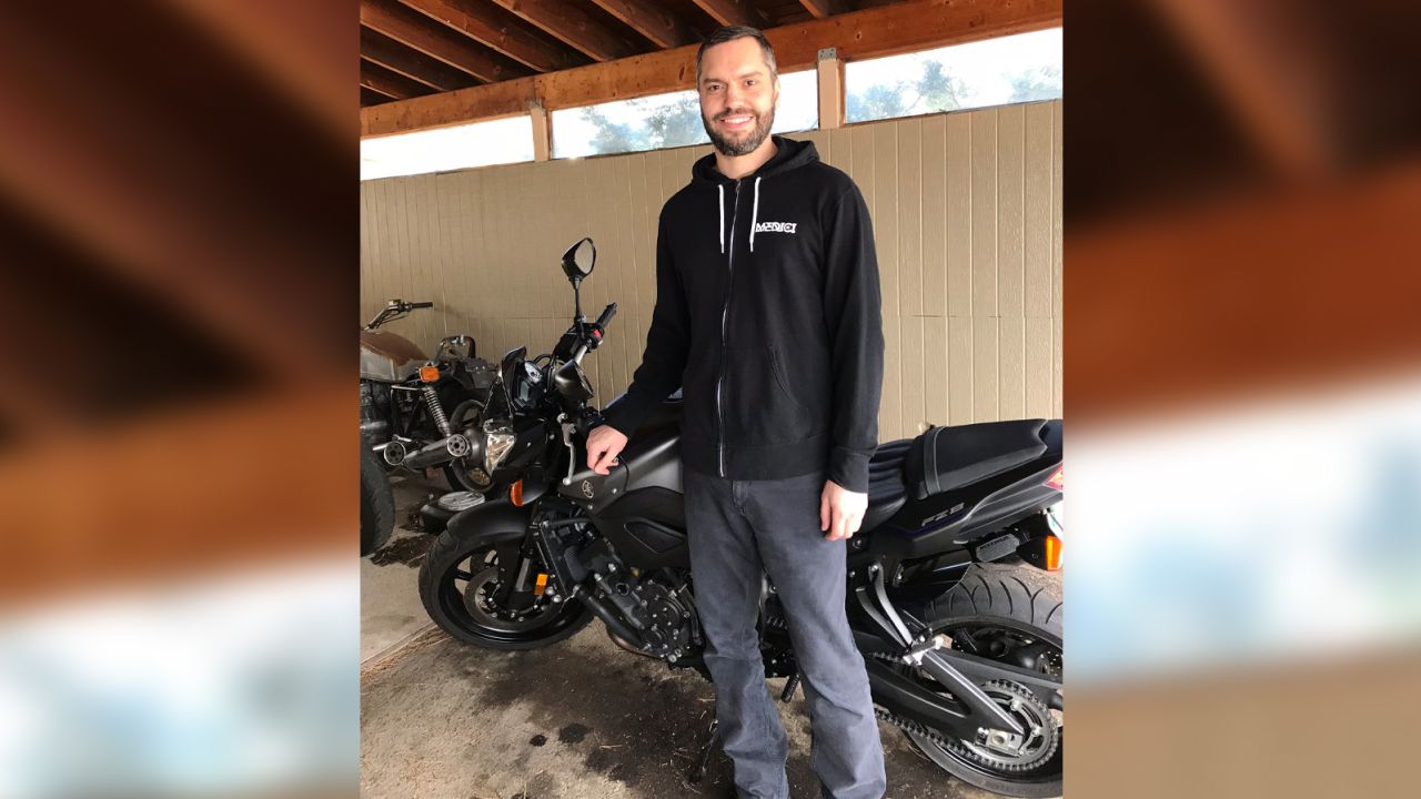 Shawn smiles near a motorcycle in February 2018.