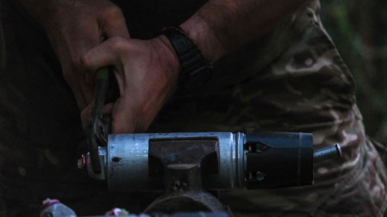 A Ukrainian soldier removes the safety on a smerch bomblet. This type of ammunition is loaded onto drones and then dropped on Russian positions.