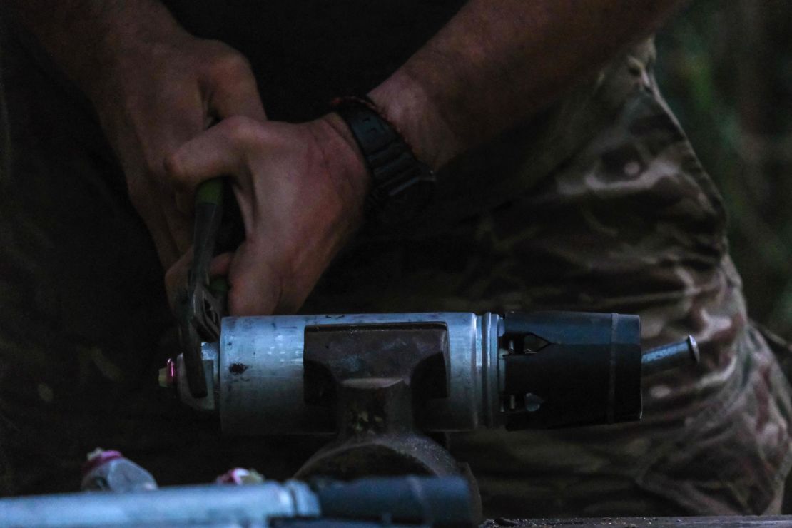 A Ukrainian soldier removes the safety on a smerch bomblet. This type of ammunition is loaded onto drones and then dropped on Russian positions.