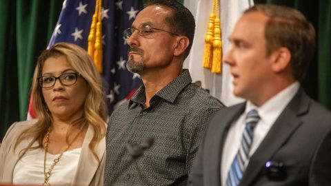 Los Angeles, CA - September 26: Laura Cabanillas, left, her husband Gerardo Cabanillas, middle,  listen as Mike Semanchik, right, Executive Director - of The Innocence Center speak during a press conference in the Hall of Justice Media Room on Tuesday, Sept. 26, 2023, in Los Angeles, CA.  Los Angeles County District Attorney George Gascón announced the exoneration of Mr. Gerardo Cabanillas after more than 28 years in prison for crimes he did not commit.  (Francine Orr / Los Angeles Times via Getty Images)