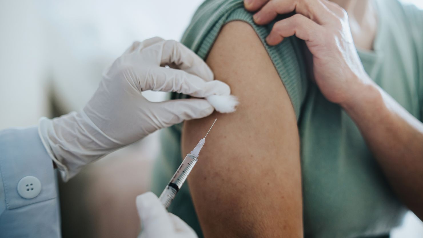 Close up of senior Asian woman getting Covid-19 vaccine in arm for Coronavirus immunization by a doctor at hospital. Elderly healthcare and illness prevention concept