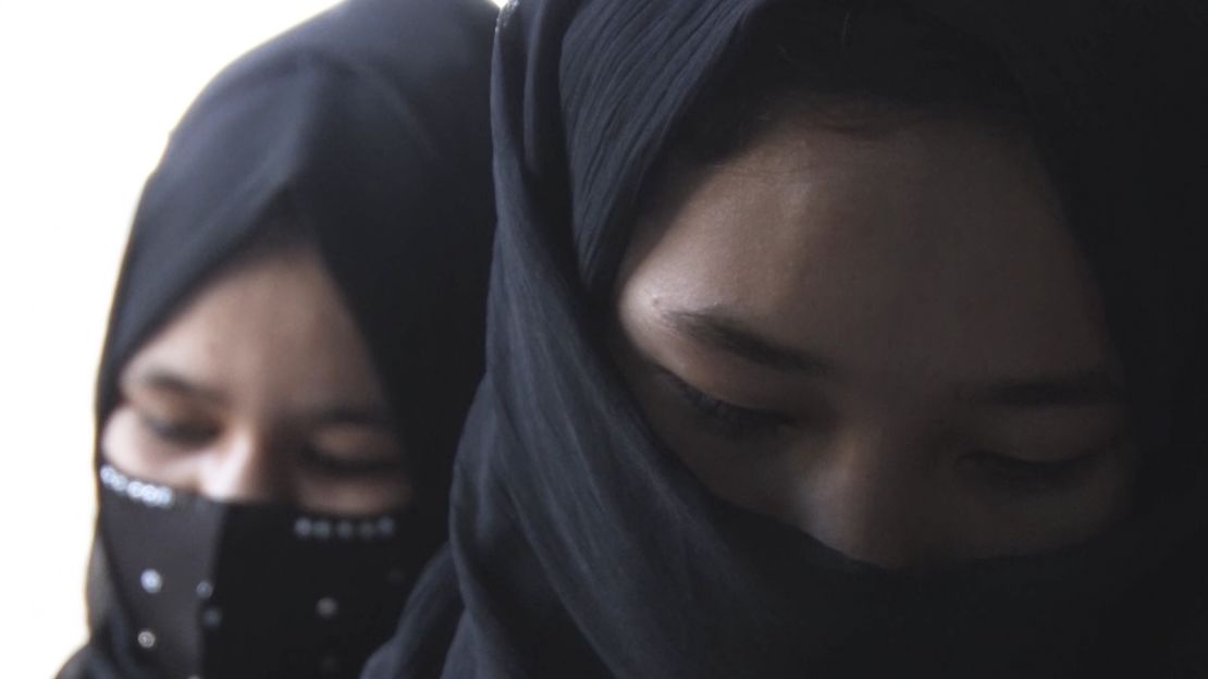 Girls, faces partially covered, attend class at a hidden school in Afghanistan.