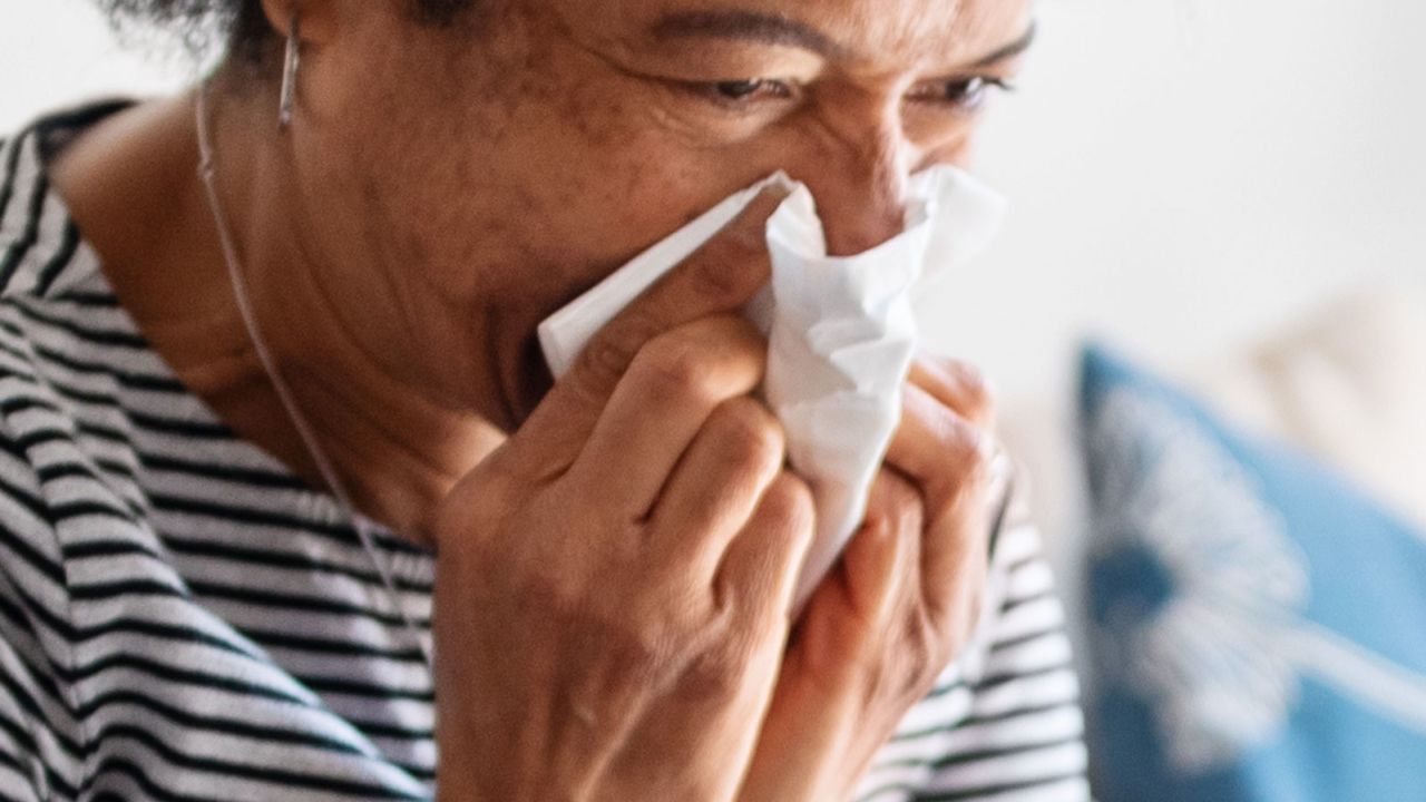 Sick woman wiping her nose with tissue paper