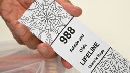 A bookmark for children with the 988 suicide and crisis lifeline emergency telephone number is displayed by Lance Neiberger, a volunteer with the Natrona County Suicide Prevention Task Force, while they speak about mental health and suicide awareness in Casper, Wyoming on August 14, 2022. - Sixteen years ago, after his son died by suicide, Lance Neiberger thought of taking his own life. Instead, the petroleum engineer -- who lives in central Wyoming -- is spearheading the difficult battle to curb the western US state's suicide rate, the highest in the nation. (Photo by Patrick T. FALLON / AFP) (Photo by PATRICK T. FALLON/AFP via Getty Images)