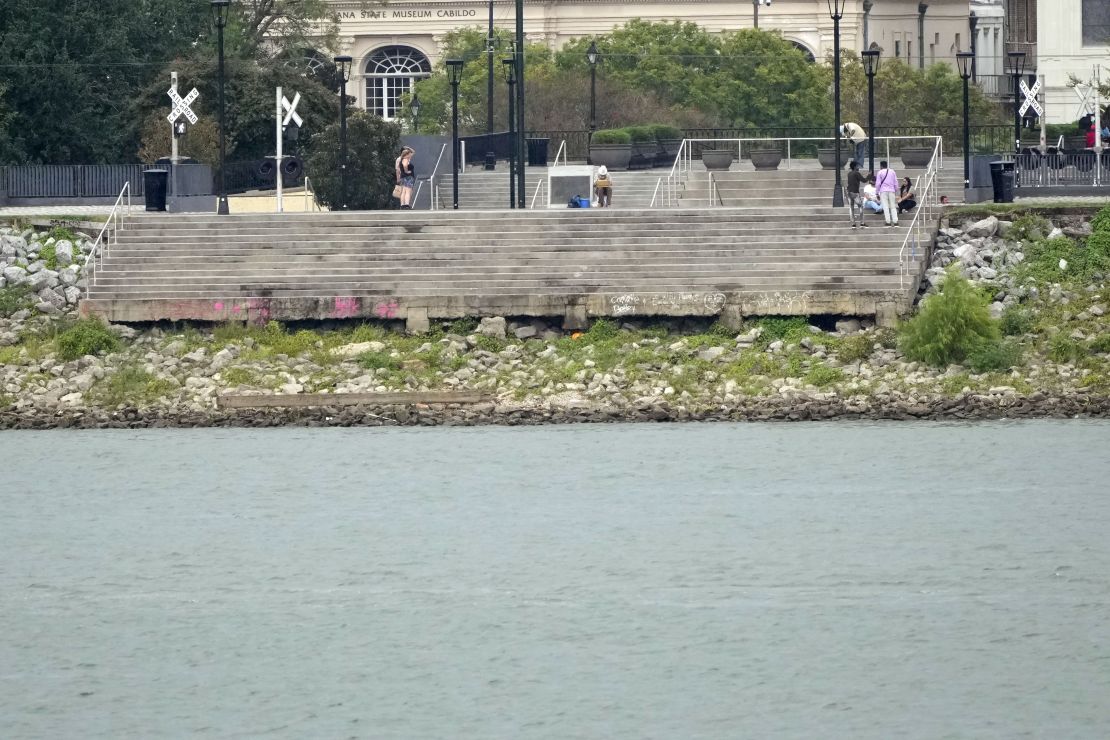 The low water level of the Mississippi River is seen as people sit on steps that normally meet the river in the French Quarter of New Orleans on Sept. 25, 2023. 