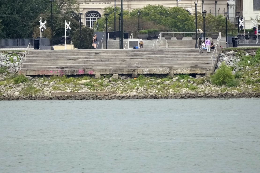 The low water level of the Mississippi River is seen as people sit on steps that normally meet the river in the French Quarter of New Orleans on Sept. 25, 2023.