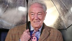 British actor Michael Gambon shelters from the rain as he arrives for the world premiere of the film Dad's Army in London on January 26, 2016. (Photo by JUSTIN TALLIS / AFP) (Photo by JUSTIN TALLIS/AFP via Getty Images)