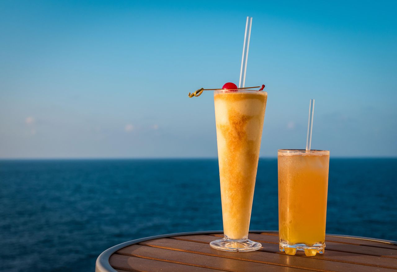 2A8XK3W Delicious holiday cocktail drinks on a table of a cruise ship. Sea background.