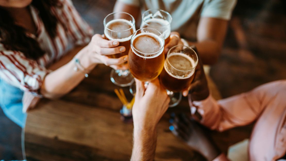 Young group of friends relaxing in a bar, drinking beer and having a celebratory toast.