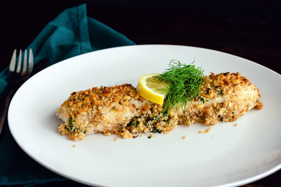 Baked white fish fillet garnished with fresh dill and a slice of lemon