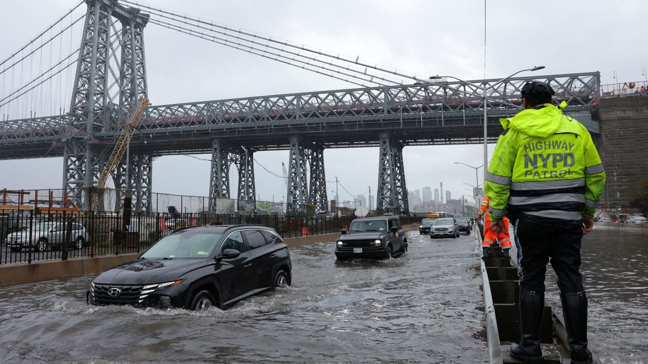 A police officer from the NYPD Highway Patrol oversees a flooded street on Friday.